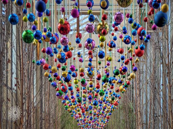 Christmas ball ornaments in a variety of colors hanging in rows from the ceiling.