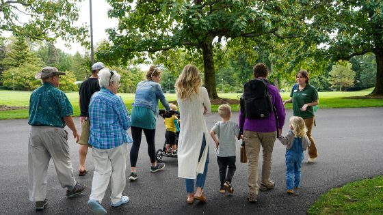 A group of people, kids and adults, walking on a paved path through Longwood Gardens.