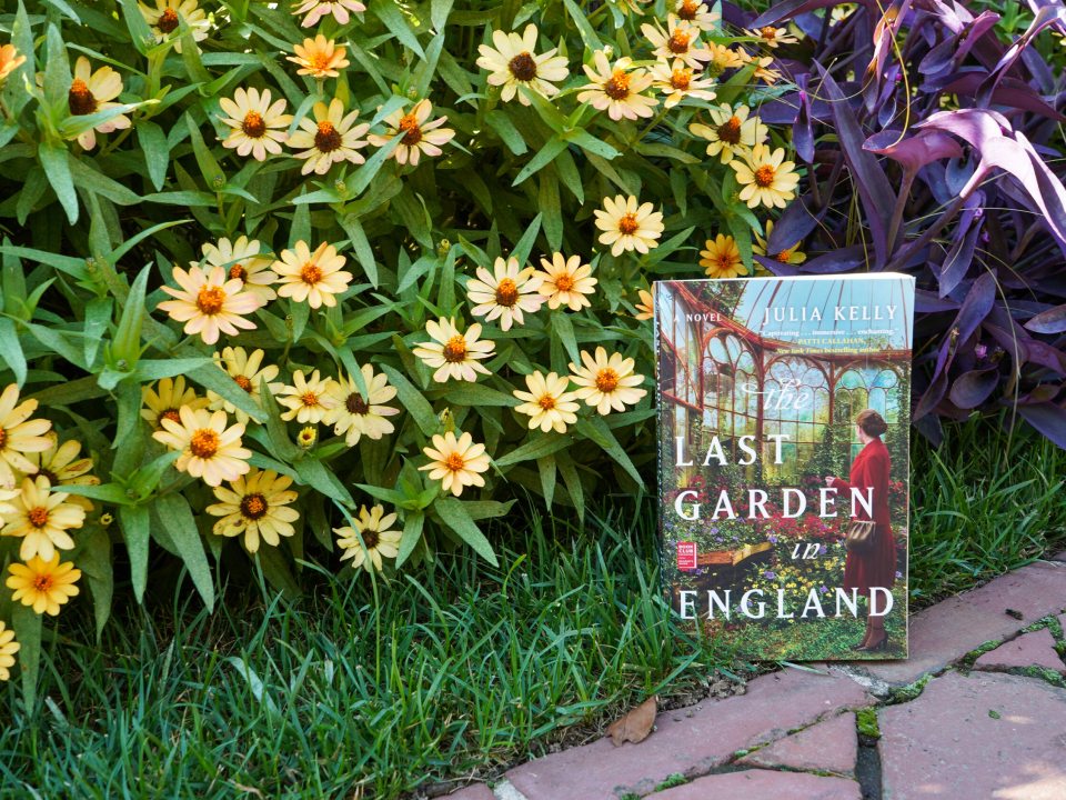 A book titled "The Last Garden in England" propped up in a flower garden bed.