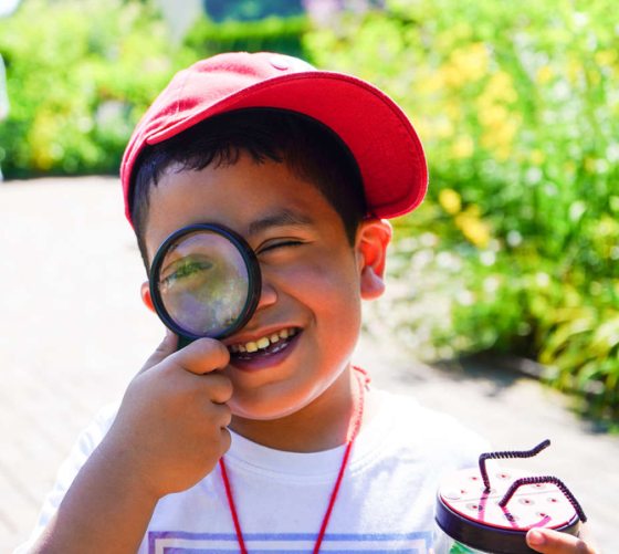 a small boy holding a magnifying glass up to his eye