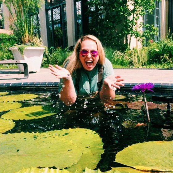 a person in waders in a waterlily pool laughing at the camera