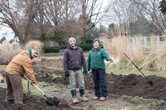 three people working dirt in a garden