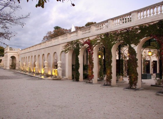 long view of stone archways; covered by vines in the forefront and backed by fountains as the view recedes