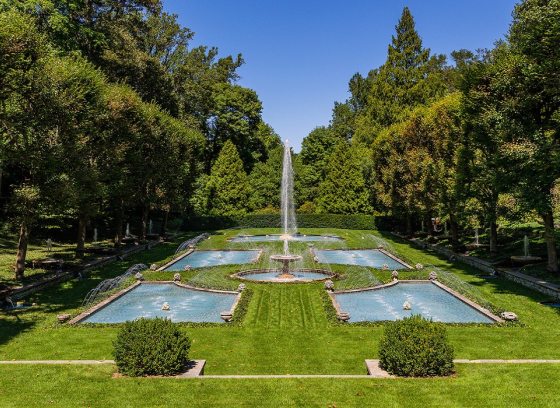 an Italian inspired garden with several fountains and green lawns