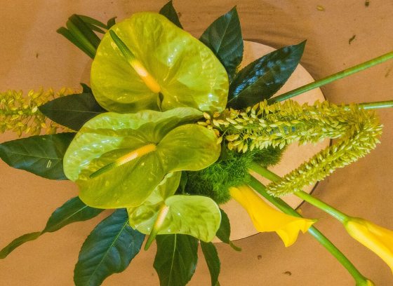 floral arrangement with green leaves and yellow lilies photographed from above