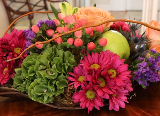 low and oblong cut flower arrangement featuring bold pinks, greens, and orange colors