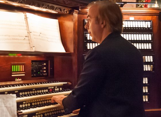  a person seated at an organ console, hands on the keys