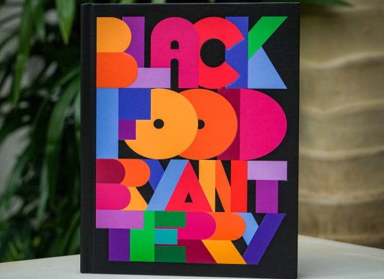 image, taken against a background of plants, of book cover entitled "Black Food" in colorful block letters