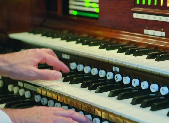 closeup of organ console, with hands on the keys