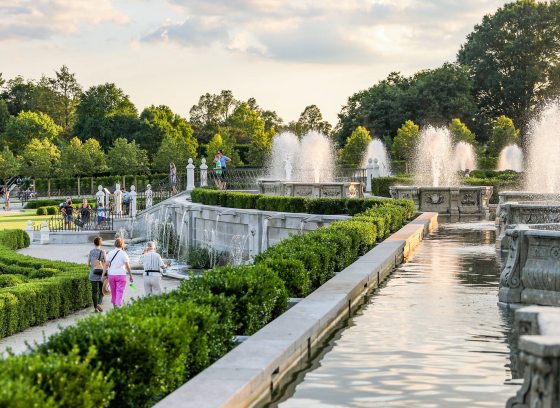 people of all ages stroll through a fountain garden