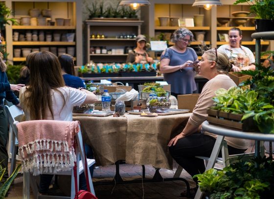 People sitting around a table in a plant shop doing a workshop. 