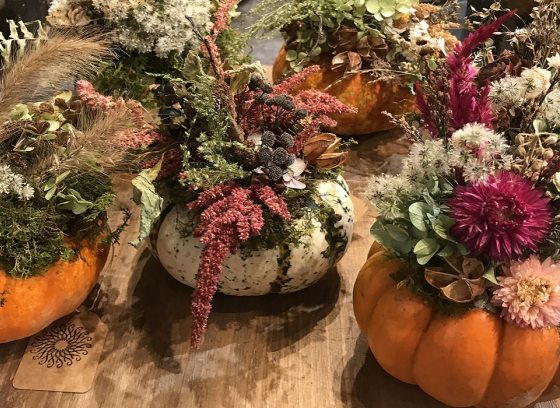 Flower centerpieces on a table using pumpkins as the base.