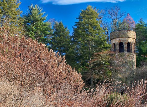 A landscape at Longwood Gardens featuring a stone tower and hillside plantings.
