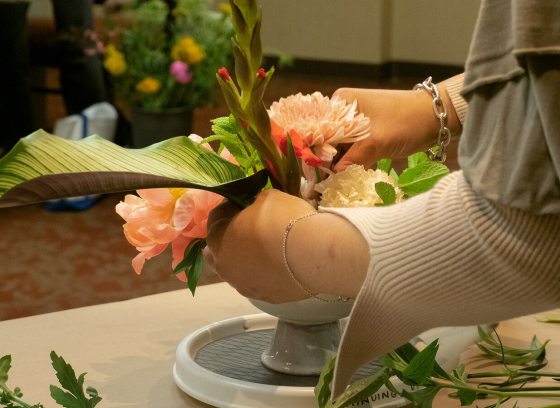 A person creating a floral arrangement in a classroom setting.
