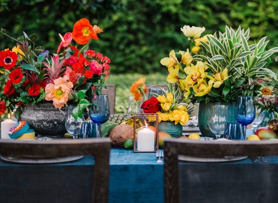 An outdoor table decorated with large tropical floral displays. 