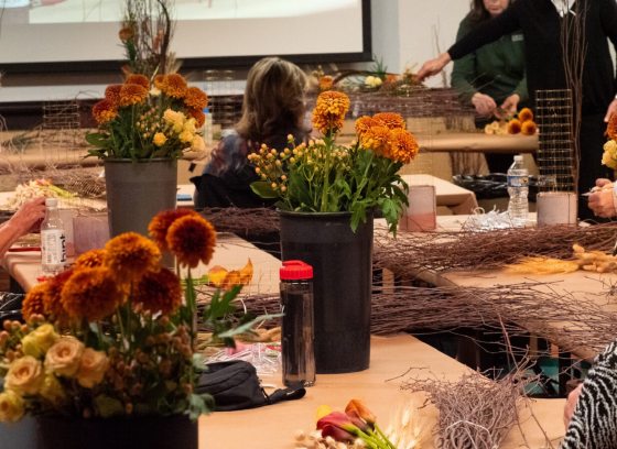 People sitting at tables preparing to create a floral design.