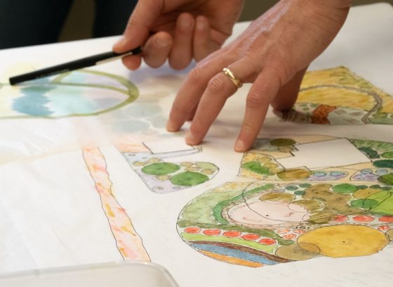 A persons hands on top of a landscape design drawing.