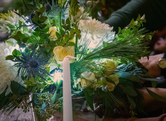 A person creating a floral arrangment from white and yellow flowers. 