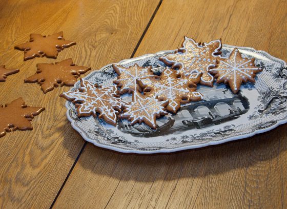 Decorated holiday cookies in the shape of snowflakes on a patterned plate.