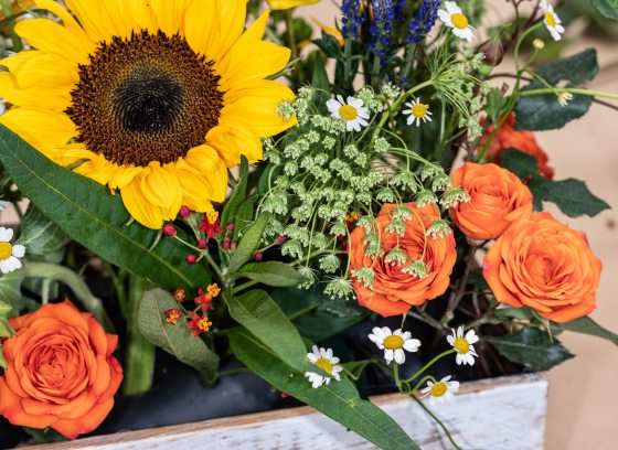 A floral arrangement featuring a bright yellow sunflower and other fall flowers.