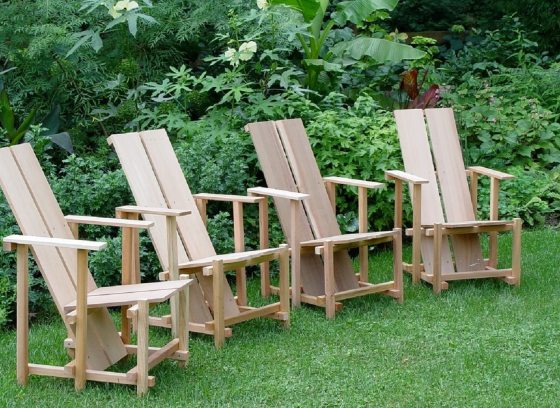 Four wooden wave hill chairs in green grass.