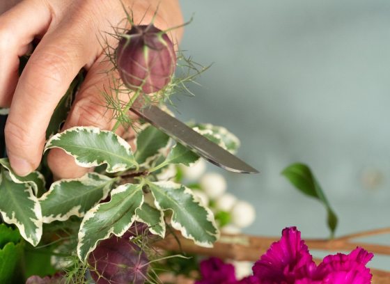 A person cutting a floral display. 