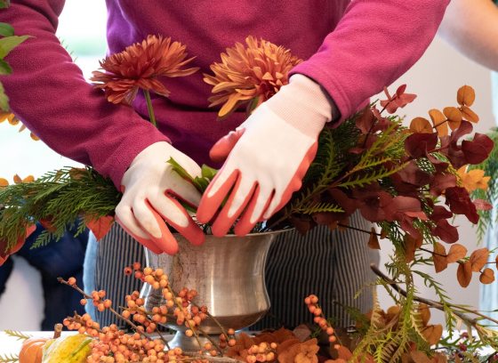 A person creating a floral arrangement in a silver vase.