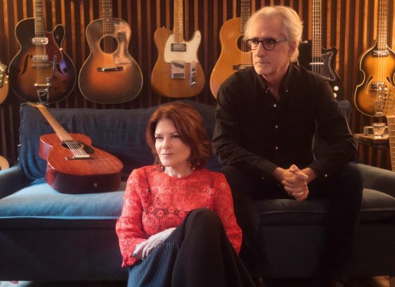 Man and woman sitting on a coach with guitars