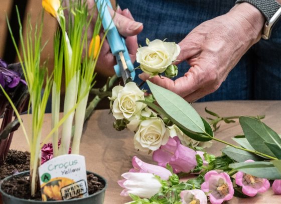 A person using scissors to shape a flower going into an arrangement. 