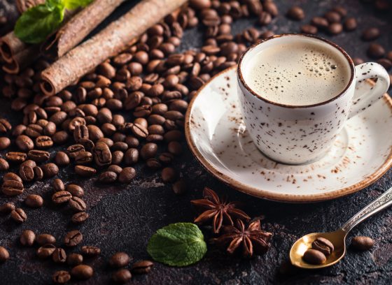 A cup of espresso surrounded by coffee beans.