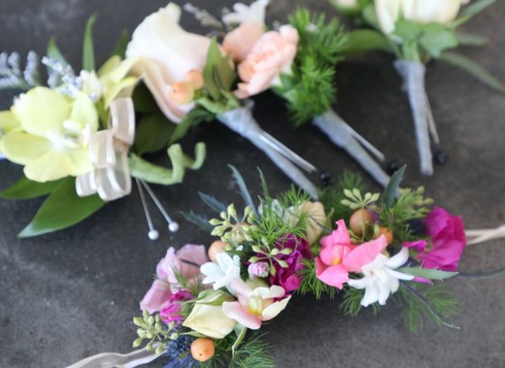 Floral boutonierre's and corsages displayed on a gray table. 