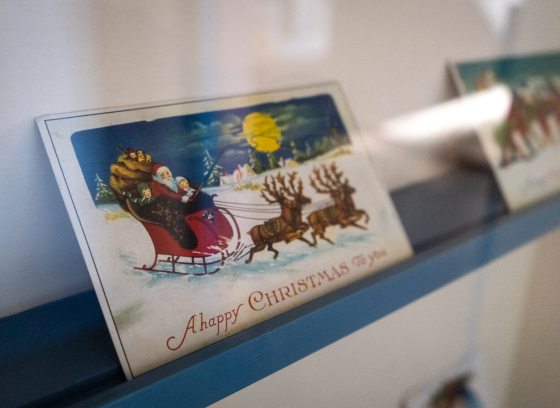 Two vintage Christmas cards on a blue ledge.