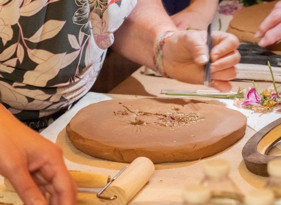 A person working with pressed flowers and clay.