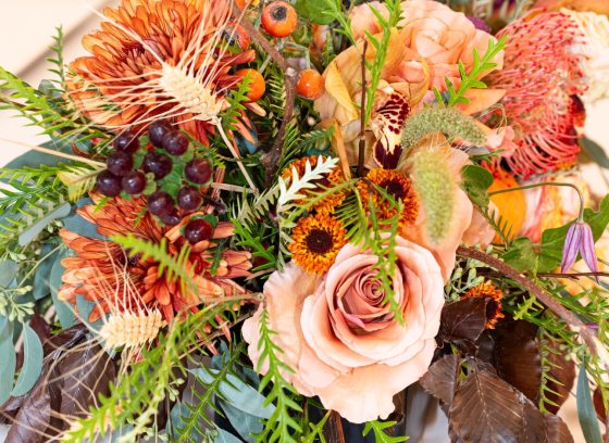 A floral arrangement in shaders of peach, featuring roses, wildflowers and other floral varieties.
