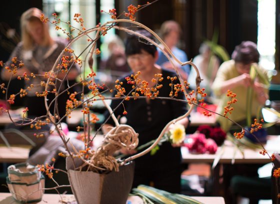 A person in a large room creating an Ikebana arrangement.