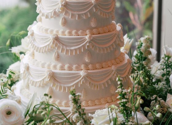 A white wedding cake set among white floral material. 