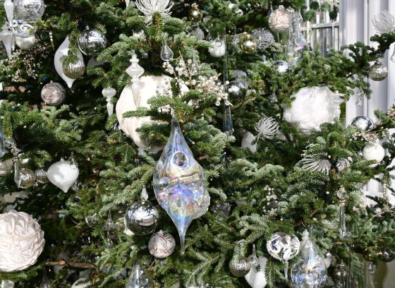 A close up of a decorated Christmas tree in while and silver ornaments.