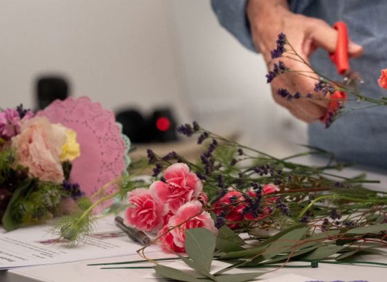 A person's hands holding floral material and clippers. 