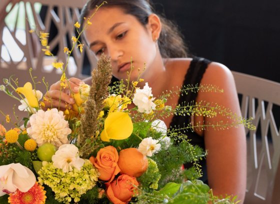A person creating a floral arrangement seated at a table.