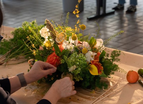 A person crafting a floral design in a white table.