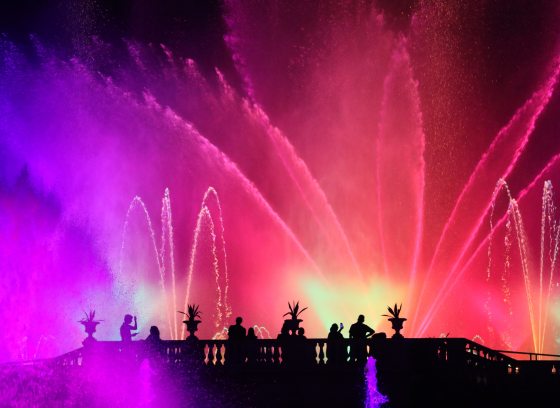 a nighttime fountain show with red, purple, and green lights
