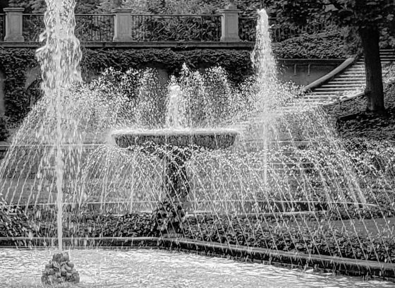 A black and white image of Italian inspired fountains in an outdoor garden.