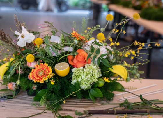 A finished floral tablescape, with yellow, orange and white blooms. 
