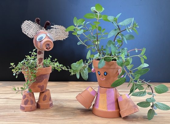 Giraffe and person crafted out of small terracotta pots planted with herbs