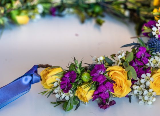 A floral crown being crafted out of purple, yellow, and white flowers. 
