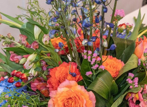 A close up of a vibrant floral arrangement featuring peach roses along with other flower and fliage types.