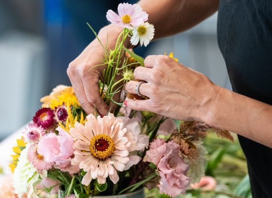 A person arranging a vibrant color floral display.