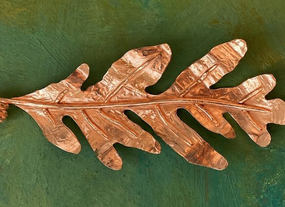 One leaf made out of copper on a green background