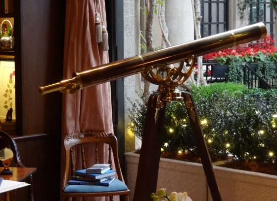 A telescope aimed outside a window in an office study. 