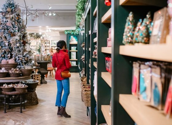 A person in a red jacket browsing shelves of holiday merchandise.